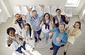 Team of people who make happy gesture by raising their hands with thumbs up demonstrating success.