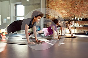 Team performance. Portrait of teenage boy doing push up, exercising together with other kids in gym. Workout on a sunny