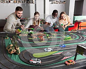 Team playing with slot car model racing track