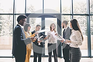 Team portrait of young and successful business people. Group of young businessmen and businesswomen discussing in modern