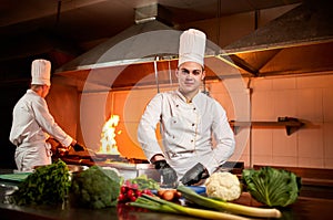 Ð team of professional chefs cook meals with frying pan and fire in the kitchen of restaurant.  Chief chef preparing dish using