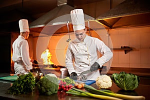 Ð team of professional chefs cook meals with frying pan and fire in the kitchen of restaurant.  Chief chef preparing dish using