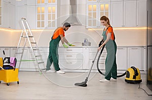 Team of professional janitors cleaning kitchen