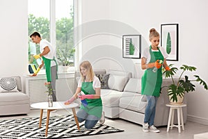 Team of professional janitors in uniform cleaning room