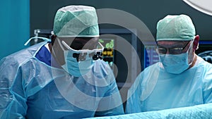 Team of professional medical surgeons performs the surgical operation in a modern hospital. Doctors are working to save