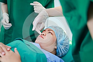 A team of professional surgeons operates the nose of an obese woman in the operating room.