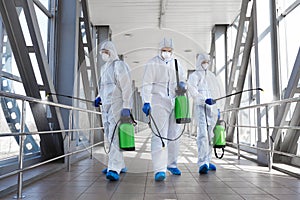 Team of professional virologists in protective suits ready for disinfection photo