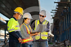 A team of professionals, civil engineers, architects are inspecting the expressway construction project site. With data on laptop