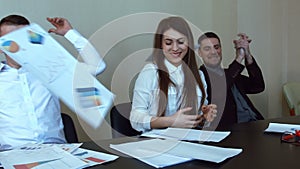 Team of professionals, sitting around a conference table throw their papers