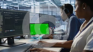 Team of programmer using green screen tablet, working in server farm photo