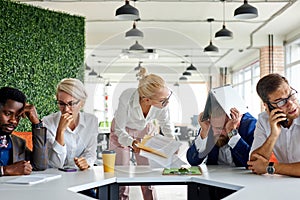 Team of sad frustrated employees receiving rebuke by shouting female executive