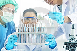 Team scientist working in laboratory. Test tubes with liquid in laboratory, Doctor hand holding dropper with dripping transparent