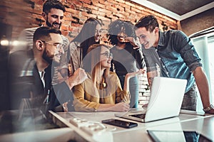 Team of six business people behind young businesswoman sitting and working on his laptop