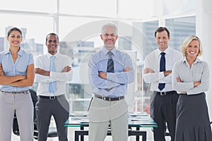 Team of smiling business people standing with arms folded