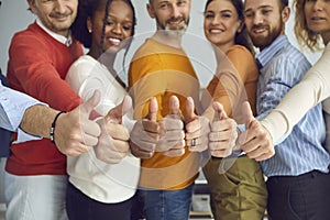 Team of smiling diverse people satisfied with successful teamwork giving thumbs up