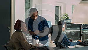 Team of software developers talking about source code running on laptop