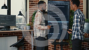Team of software engineers leaving after analyzing source code on wall screen tv comparing errors