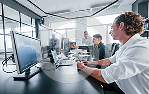 Team of stockbrokers works in modern office with many display screens photo