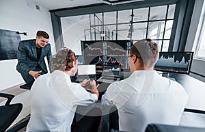 Team of stockbrokers works in modern office with many display screens photo