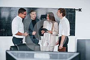 Team of stockbrokers works in modern office near blackboard