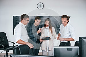 Team of stockbrokers works in modern office near blackboard