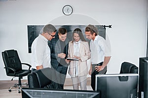 Team of stockbrokers works in modern office near blackboard photo