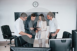 Team of stockbrokers works in modern office near blackboard