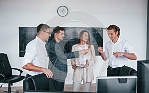 Team of stockbrokers works in modern office near blackboard photo