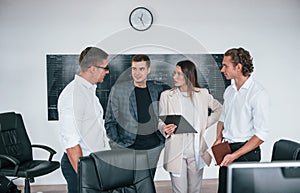 Team of stockbrokers works in modern office near blackboard photo