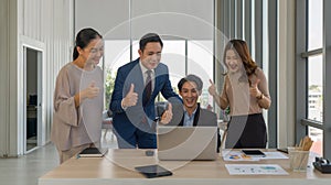 Team of successful business people gather around a table raise finger thumb up with a smile. Concept of leadership