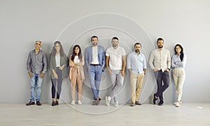 Team of successful and modern business people standing leaning against gray wall in empty office.