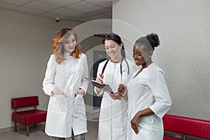 A team of successful women healthcare doctors discuss medical issues in the hospital corridor.