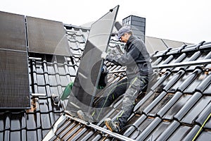 Team of technicians installing solar panels on the roof of a house