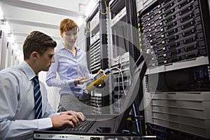 Team of technicians using digital cable analyser on servers