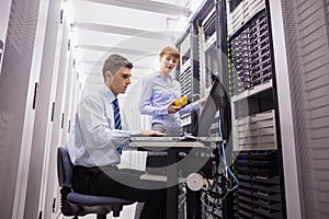 Team of technicians using digital cable analyser on servers