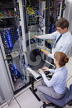 Team of technicians using digital cable analyser on servers