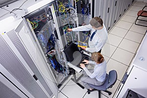 Team of technicians using digital cable analyser on servers