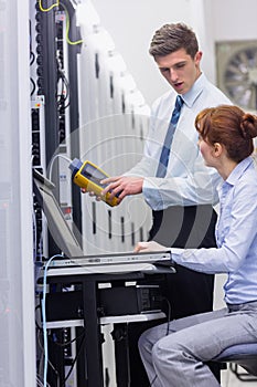 Team of technicians using digital cable analyser on servers