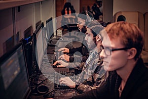 Team of teenage gamers plays in a multiplayer video game on pc in a gaming club.