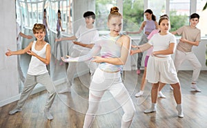 Team of teenagers rehearsing modern dances in dance hall