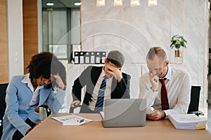 Team thinking of problem solution at office meeting, sad diverse business people group shocked by bad news, upset colleagues in