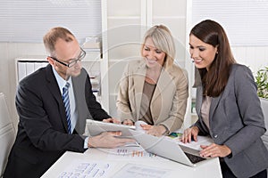 Team of three business people sitting together at desk in a meet