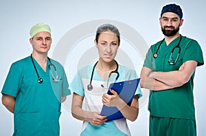 A team of three young doctors. The team included a doctor and a woman, two men doctors. They are dressed in scrubs. On the necks
