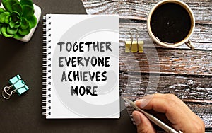 TEAM - together everyone achieves more - motivational text on a clipboard with a cup of coffee