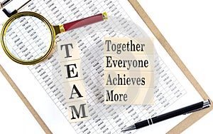 TEAM together everyone achieves more text on wooden block on chart background