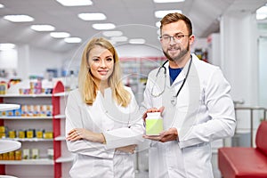 Team of two pharmacists is showing medicine box presentation in pharmacy store