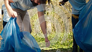 Team of volunteers collecting rubbish to fix pollution problem within the forest habitat