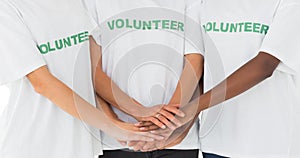 Team of volunteers putting hands together photo