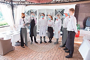 A team of waiters conduct a briefing on the summer terrace of the restaurant