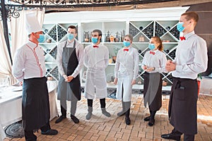 A team of waiters conduct a briefing on the summer terrace of the restaurant